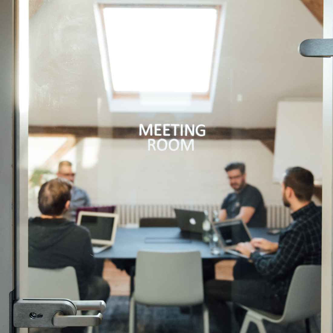 Blick in einen Meetingraum von Bleech, das Wort Meeting Room an der Glastür ist fokussiert.