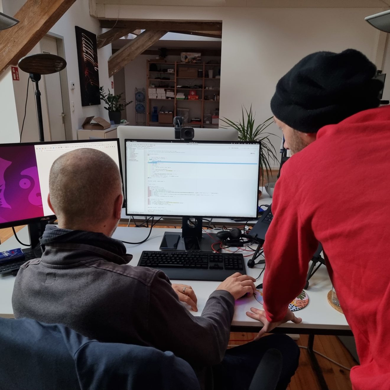 Zwei Bleech Mitarbeiter schauen konzentriert auf einen Computerbildschirm, von hinten.